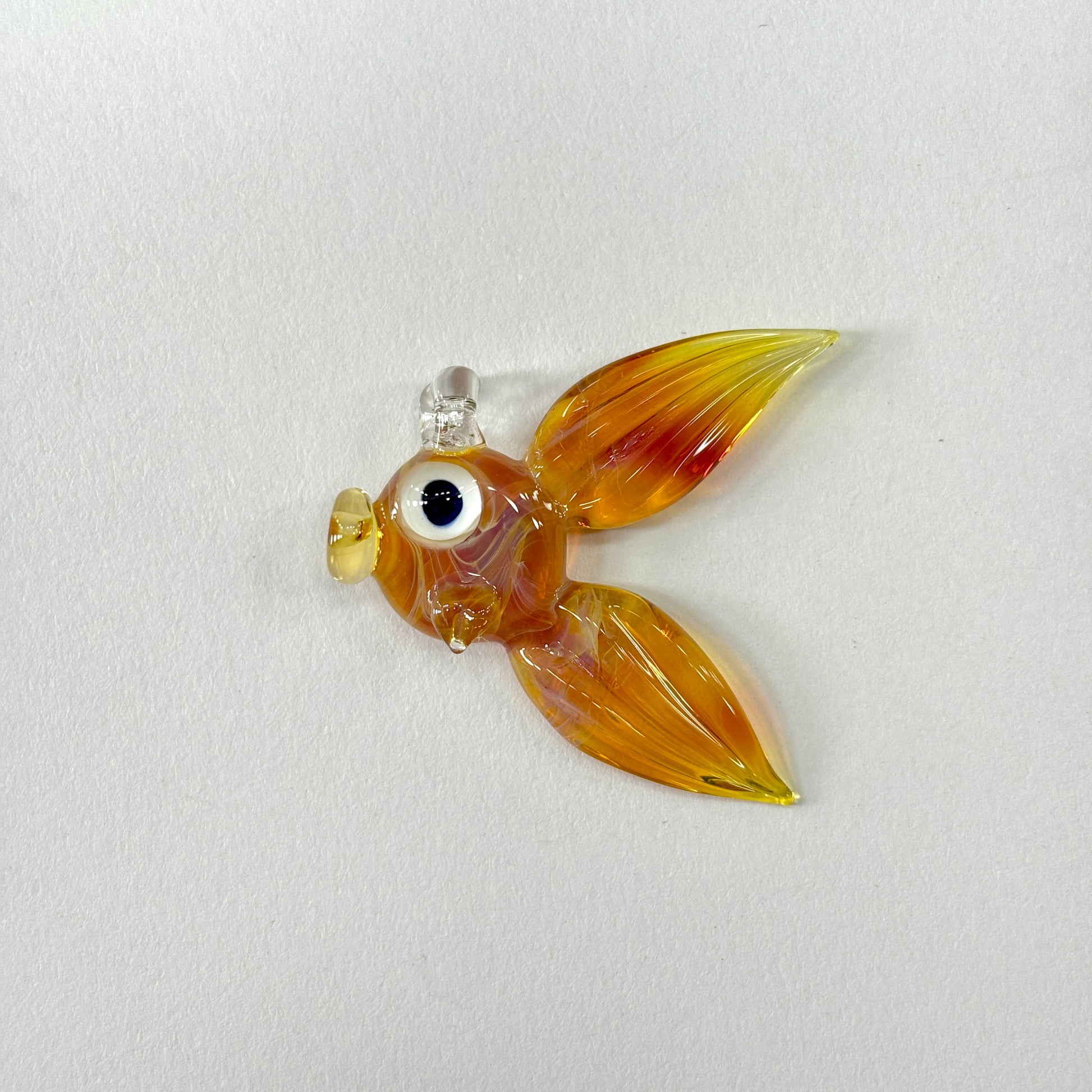 Glass fish ornament, in the borosilicate color Amber Purple on a white background